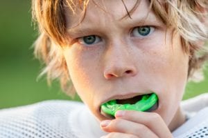 Boy putting in a mouthguard before playing football