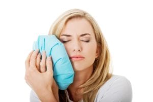 Woman holding a cold compress against her cheek