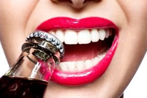 Woman biting on bottle cap with her teeth